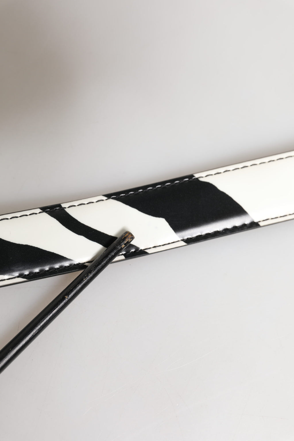 Svartvitt läderbälte med silverfärgad metallspänne