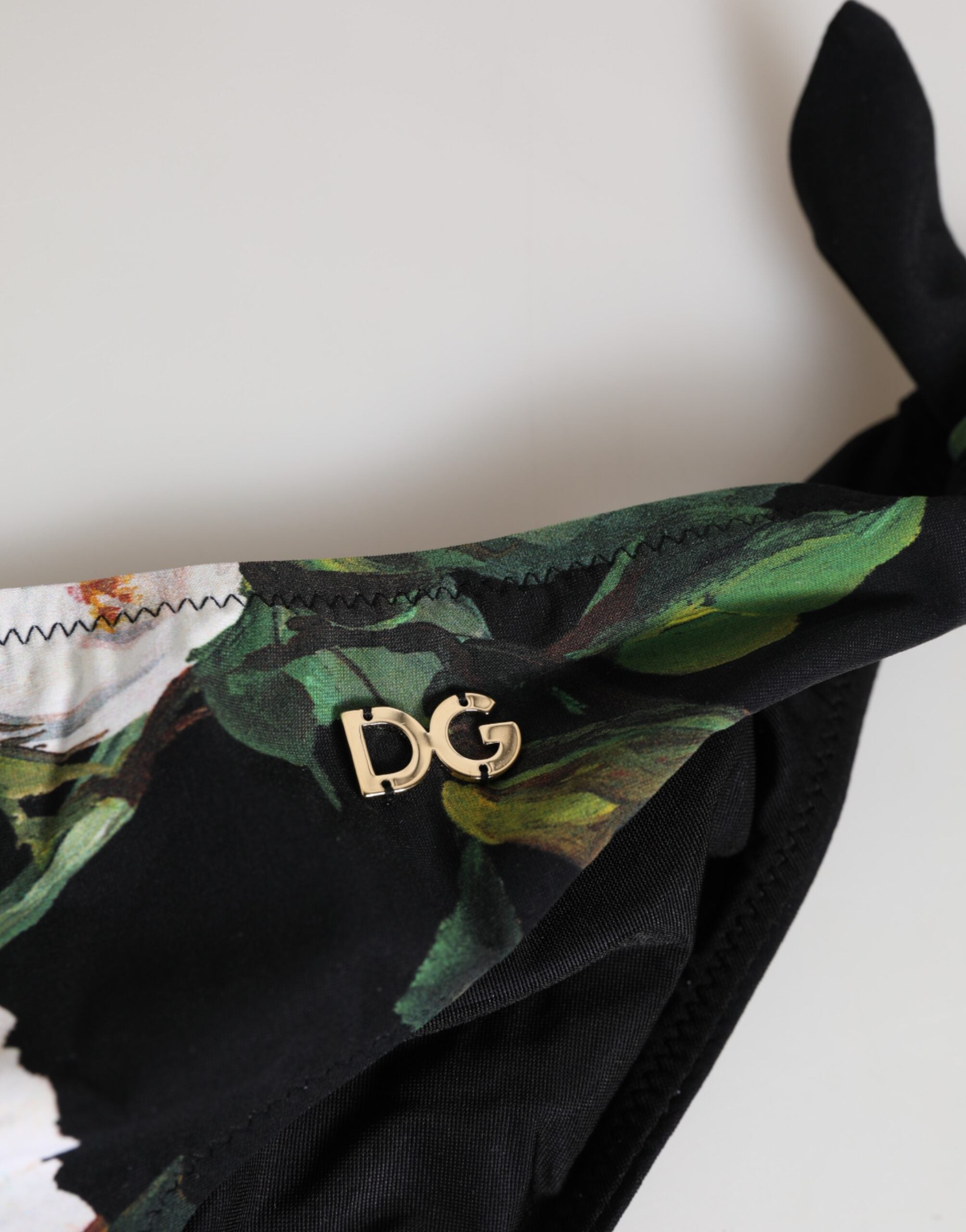 Svart bikiniunderdel med blommigt knytband i sidan och badkläder